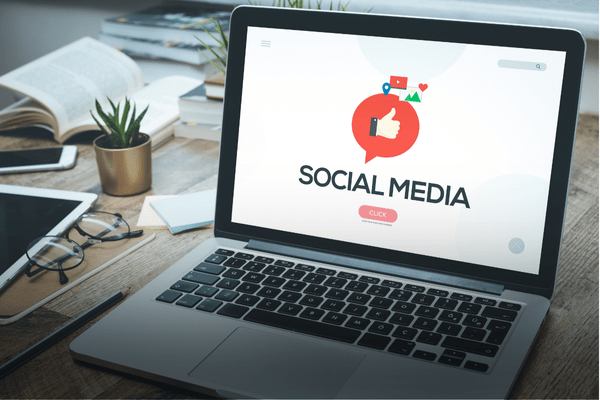 Laptop displaying a social media dashboard illustration on a desk — representing nonprofit engagement strategy and social media management